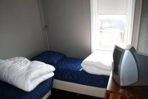 a small bedroom with two beds and a television at Liguster 56* in Nieuwvliet