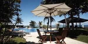 uma mesa e cadeiras com um guarda-sol ao lado de uma piscina em Villa Stefan em Pantai Anyer