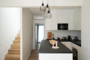 a kitchen with white cabinets and a black counter top at Casa Fuerteremote - new and modern house with office in Corralejo in La Oliva