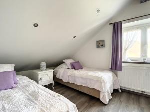 a attic bedroom with two beds and a window at Au Chat’Moineau in Aywaille