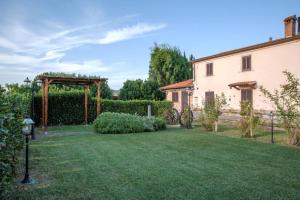 einen Garten mit einer Pergola und einem Gebäude in der Unterkunft Le Gerlette - La Stalla in Braccagni