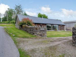 a stone house with a stone wall next to a road at 2 Bed in Kinnerton CHL34 in Kinnerton