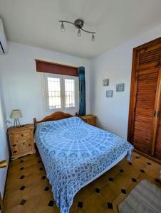 a bedroom with a bed with a blue comforter and a window at Stunning Villa Felipe, with private pool & hot tub in Almogía