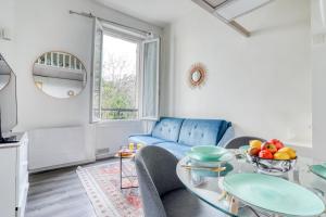 - un salon avec un canapé bleu et une table dans l'établissement Chic Appartement Climatisé à 10 Minutes de Paris: Confort et Élégance, à Maisons-Alfort