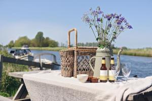 een picknicktafel met flessen wijn en een mand met bloemen bij Smuk Grutte Bell Tent in Echtenerbrug