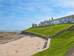 a building on top of a hill next to the beach at 2 Bed in Seahouses CN198 in Seahouses