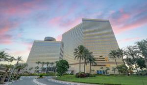 zwei hohe Gebäude mit Palmen vor einer Straße in der Unterkunft Hyatt Regency Dubai - Corniche in Dubai