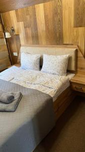 um quarto com uma cama grande e uma cabeceira em madeira em Lastivka Guest House em Yablunytsya