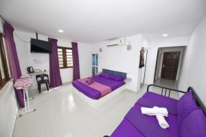 een kamer met een paars bed en een bank bij OYO 90908 Noor Arfa River Chalet in Kuala Terengganu