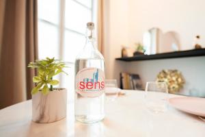 una bottiglia d'acqua seduta su un tavolo con una pianta di Le Laurencin Sens - Le Zen a Sens