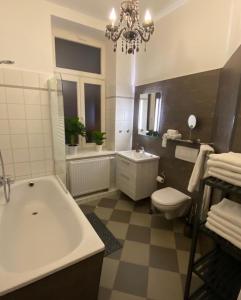 a bathroom with a tub and a toilet and a chandelier at N A U T I C A - ruhige maritime Ferienwohnung mit Balkon familienfreundlich in Rostock