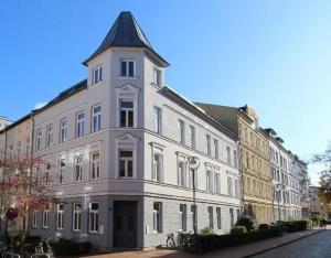 a large white building with a black roof at N A U T I C A - ruhige maritime Ferienwohnung mit Balkon familienfreundlich in Rostock