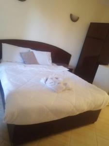 1 cama con sábanas blancas y cabecero de madera en Eiffel Hotel Hurghada, en Hurghada