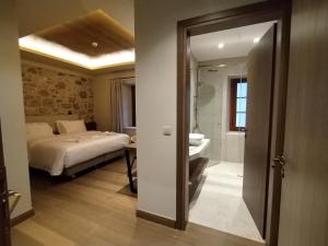 a bedroom with a bed and a bathroom with a sink at Μikri Arktos Boutique Hotel in Dhimitsana