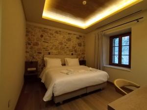 a bedroom with a large bed with a stone wall at Μikri Arktos Boutique Hotel in Dhimitsana