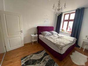 Schlafzimmer mit einem Bett, einem Fenster und einem Kronleuchter in der Unterkunft Traumwohnung STÖRTEBEKER ruhig & großzügig zentral in Rostock