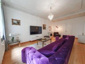 a purple couch in a living room with a tv at DEUTSCHE VILLA - DELUXE APARTMENT mit Sauna und großem Garten in Rostock
