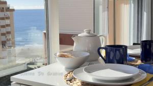 einen Tisch mit einer Teekanne und einer Schüssel Essen in der Unterkunft Primera línea de playa, deditos de los pies en la arena !! Carabela-C704 Piscina Torrox-Costa in Torrox Costa