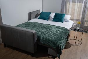 1 cama con edredón verde y blanco y almohadas azules en ResiNest Apartamenty Kameralna Wesoła, en Białystok