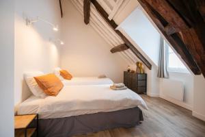 a bedroom with a large bed with white sheets and orange pillows at Le Laurencin Sens - Le Comble - Cœur de ville in Sens