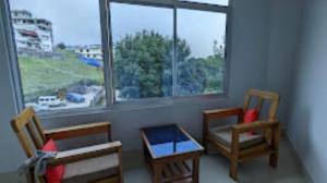 a room with two chairs and a table and a window at Hotel Dewa Elegance Tawang in Tawang