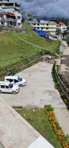 dos autos blancos estacionados en un estacionamiento en Hotel Dewa Elegance Tawang en Tawang