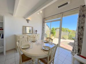 a dining room with a table and a large window at Agréable maison avec terrasse et piscine collective -6PQ32 in Le Barcarès