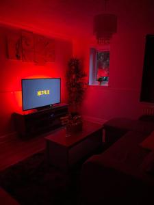 a living room with a tv in a red room at Watford Cozy Full Home W Parking - Perfect for Harry Potter Studios! in Leavesden Green