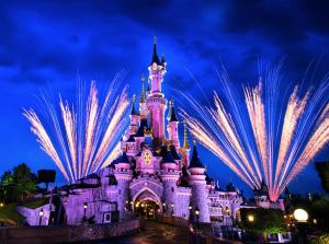 a disney castle lit up at night with fireworks at Disneyland Paris appartement Bmyguest in Chessy