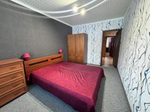 ein Schlafzimmer mit einem roten Bett und einer Holzkommode in der Unterkunft Real appartments in Visaginas