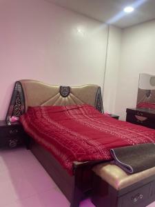 a bed with a red comforter in a room at الجامعين ستار in Ruqaiqah