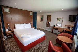 a hotel room with a bed and a desk and chairs at Best Western Brome Grange Hotel in Brome