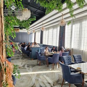 un groupe de personnes assises à table dans un restaurant dans l'établissement HAYAT PLAZA HOTEL & Spa, à Samarcande