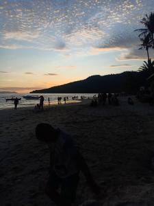 grupa ludzi na plaży o zachodzie słońca w obiekcie D' pamor Homestay w mieście Halangan