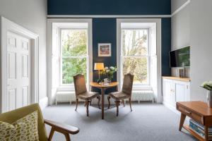 ein Wohnzimmer mit einem Tisch und Stühlen sowie 2 Fenstern in der Unterkunft Spacious, Light-filled Central Period Apartment in Bath