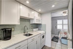 een keuken met witte kasten en een spoelbak bij Seaside Elegance Your Coastal Getaway in Myrtle Beach