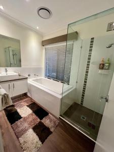 a bathroom with a tub and a glass shower at Private Gem in Pacific Pines in Gold Coast