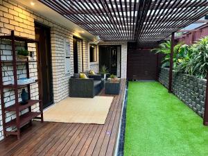 an outdoor patio with a wooden deck with grass at Private Gem in Pacific Pines in Gold Coast