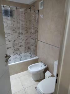 a bathroom with a toilet and a shower with drawings on the wall at Flores Finesse in Buenos Aires
