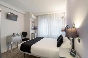 a hotel room with a bed and a desk and chair at Alda Centro Zamora in Zamora