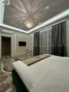 - une grande chambre avec un grand lit et un lustre dans l'établissement HAYAT PLAZA HOTEL & Spa, à Samarcande