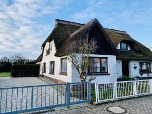 a house with a thatched roof and a fence at KAPITÄNS HUS - traditionelles Reethaus strandnah, Sauna, großer Garten, PKW-Stellplätze in Graal-Müritz