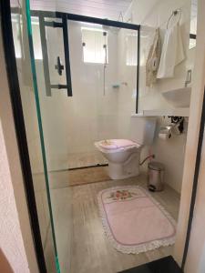 a bathroom with a toilet and a glass shower door at Chalé rosa in Resende