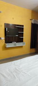 TV de pantalla plana en una pared amarilla en Atithi Hotel, en Paliā Kalān