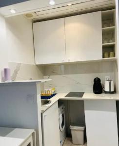 a kitchen with white cabinets and a washing machine at Appartement moderne Quartier Saint Lazare in Paris