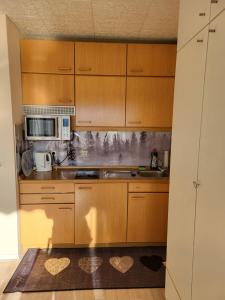 a kitchen with wooden cabinets and a microwave at FeWo Talblick 22 in Bad Lauterberg