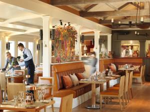 un restaurant avec des tables et des chaises et un homme debout au milieu dans l'établissement The Grove, à Chandler's Cross