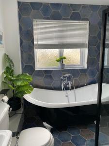 a bathroom with a bath tub and a window at Lobster Cottage - Stylish 3 Bedroom Cottage in heart of Tenby Town, Pembrokeshire in Pembrokeshire