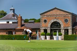 Un uomo che gioca a golf di fronte a un edificio di The Grove a Chandler's Cross