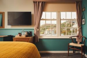 a bedroom with a bed and a large window at The Old Success Inn in Sennen Cove